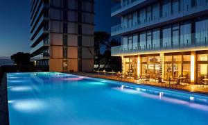 a swimming pool in front of a building at night at Miramare Magnetic Beach Hotel in Kobuleti