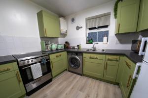 a kitchen with green cabinets and a dishwasher at Spacious & Central Ground Floor Apt in Royal Tunbridge Wells