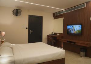1 dormitorio con 1 cama y TV de pantalla plana en Hotel JK Celebration, en Jabalpur