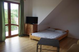 a bedroom with a bed and a television and a balcony at Gosciniec Wydminy in Wydminy