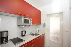 a kitchen with red cabinets and a sink and a microwave at Strandschloesschen-Haus-II-WE-18-9723 in Kühlungsborn