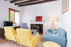 a living room with a blue couch and yellow chairs at Can Bessó Mancor de la Vall in Mancor del Valle