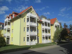 キュールングスボルンにあるStrandschloesschen-Haus-II-WE-18-9723の白いバルコニー付きの大きな黄色のアパートメントビル