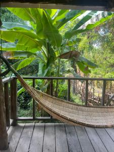 a hammock on a deck with a large plant at Mr. Loy Guesthouse in Don Det