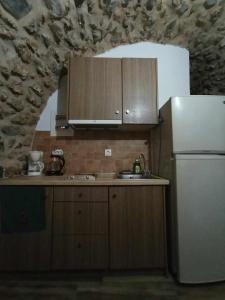 cocina con armarios de madera y nevera blanca en Ο ΘΟΛΟΣ en Stemnitsa