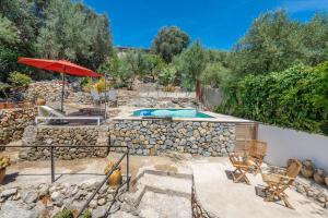 eine Terrasse mit einem Pool, einem Sonnenschirm und Stühlen in der Unterkunft Can Bessó Mancor de la Vall in Mancor del Valle