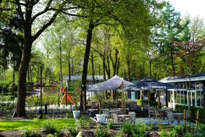 een groep tafels en stoelen met parasols in een park bij De Rimboe en de Woeste Hoogte in Hoenderloo