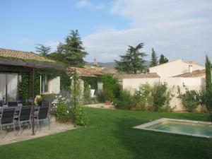 a garden with chairs and a swimming pool at Le Chat Sur Le Toit in Lourmarin