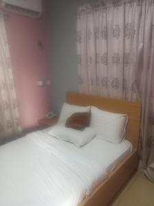 um quarto com uma cama com lençóis brancos e almofadas em CRYSTAL SUITES em Akure