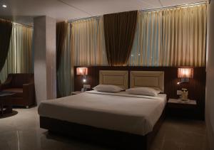 a bedroom with a large bed with two lamps at Hotel JK Celebration in Jabalpur