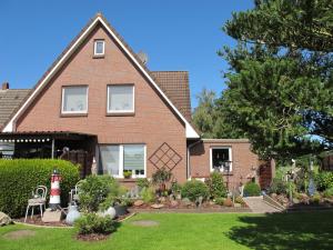 a red brick house with a garden in front of it at Ferienwohnung ERNA HORS110 in Wangerland