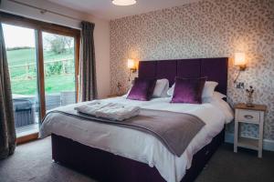 1 dormitorio con 1 cama grande con almohadas moradas en Beautiful cottage in idyllic countryside setting en Montgomery