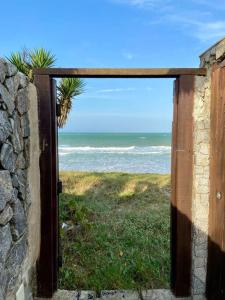 une porte ouverte sur une vue sur l'océan dans l'établissement Casa Búzios pé na areia, à Búzios