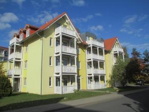 a large yellow building with white balconies on a street at Strandschloesschen-Haus-II-WE-3-9734 in Kühlungsborn
