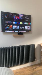 a flat screen tv hanging on a wall with a radiator at Swallows Nest in Gotham