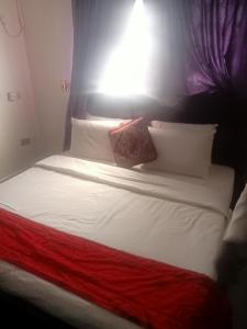 łóżko z białą pościelą i poduszkami w pokoju w obiekcie CRYSTAL SUITES w Akure