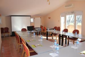 une salle de conférence avec des tables et des chaises et un tableau blanc dans l'établissement Logis Hôtel Le Mas De Jossyl, à La Roque-dʼAnthéron