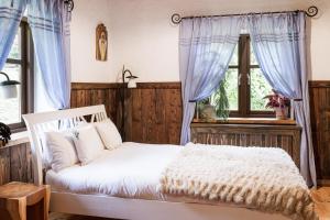 a bedroom with a white bed with blue curtains at Maciejewka in Zahoczewie