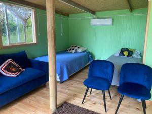 1 dormitorio con 1 cama y 2 sillas azules en Los carbon, en Ancud