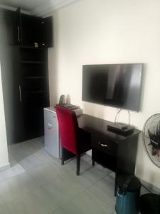 einen Schreibtisch mit einem Monitor und einem roten Stuhl in einem Zimmer in der Unterkunft CRYSTAL SUITES in Akure