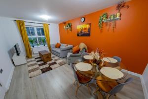 ein Wohnzimmer mit orangefarbenen Wänden sowie einem Tisch und Stühlen in der Unterkunft Spacious & Central Ground Floor Apt in Royal Tunbridge Wells