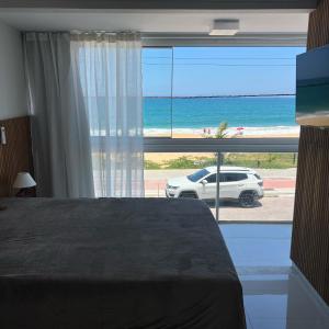 a bedroom with a large window with a view of the beach at Triplex Vista Azul in Rio das Ostras