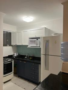 a kitchen with white cabinets and a white refrigerator at Triplex Vista Azul in Rio das Ostras