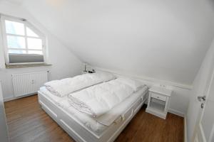un lit blanc dans une chambre avec une fenêtre dans l'établissement Atlantik - Strandstr 15, App 12, à Wenningstedt