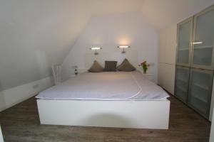 um quarto com uma cama branca num sótão em Feldmarkstraße 5, App 10 em Wenningstedt