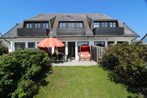 a house with an umbrella and a table and chairs at Dünental 6b in Wenningstedt