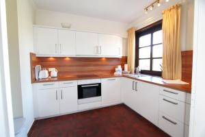 a white kitchen with white cabinets and a window at Dünental 6b in Wenningstedt