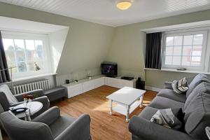 uma sala de estar com um sofá e uma televisão em Steffi - Ostmarkstr 20, App 2 em Wenningstedt