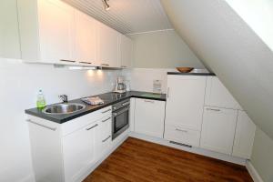 uma cozinha com armários brancos e um lavatório em Steffi - Ostmarkstr 20, App 2 em Wenningstedt