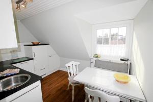 uma cozinha branca com um lavatório e uma mesa em Steffi - Ostmarkstr 20, App 2 em Wenningstedt