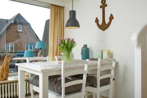 uma mesa de jantar branca com cadeiras brancas e uma janela em Risgap 5 B, App 24 em Wenningstedt