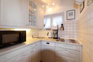 uma cozinha branca com um lavatório e um micro-ondas em Residenz Nikolas- Grenzweg 12, App 2 em Wenningstedt