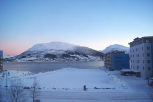 uma pessoa parada na neve ao lado de uma montanha em True Vesterålen Hotel em Sortland