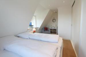 um quarto com uma cama branca num quarto em Horsa Hüs - Westerlandstr 22 B em Wenningstedt