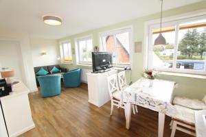 - un salon avec une table à manger et une télévision dans l'établissement Haus Günther - Mittelweg 1, App 2, à Wenningstedt