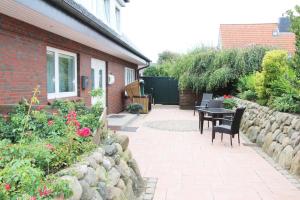 un patio avec une table et des chaises à côté d'un bâtiment en briques dans l'établissement Haus Günther - Mittelweg 1, App 2, à Wenningstedt 9 autres photos