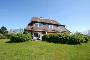 a large house with bushes in the yard at Denghoog- Osetal 10, App 2 in Wenningstedt