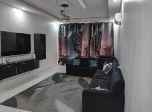 ein Wohnzimmer mit einem Sofa und einem Flachbild-TV in der Unterkunft Luxury 2- Apartment Furnished luxury residence in Cocody