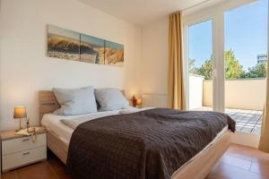 1 dormitorio con cama y ventana grande en Strandpark-Grossenbrode-Haus-Leuchtturm-Wohnung-8, en Großenbrode