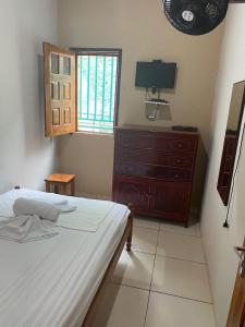a bedroom with a bed and a dresser and a window at casa pedacinho do morro in Bom Jesus da Lapa