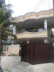 una casa con un cancello e una palma di Ayub House a Karachi