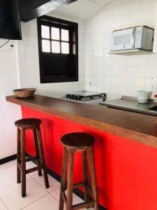 a kitchen with two wooden stools at a counter at Praia de Geribá C 1 in Búzios