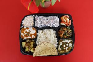 um recipiente preto de alimentos com arroz e diferentes alimentos em Green View Residency em Greater Noida
