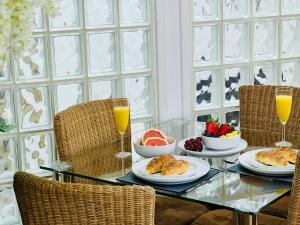 a table with a breakfast of croissants and fruit and orange juice at Safari Lodge - Close to Shopping Centre and Restaurants, Free Parking, Stylish and Amazing Artwork in Burton upon Trent