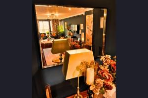 a mirror reflecting a living room with a lamp and flowers at The Kensington in London