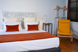 Un dormitorio con una cama con almohadas naranjas y una silla. en Casa do Briamante 6, en Sintra